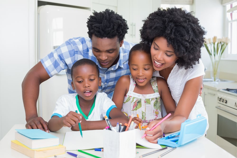 Happy parents helping children with homework at home in the kitchen